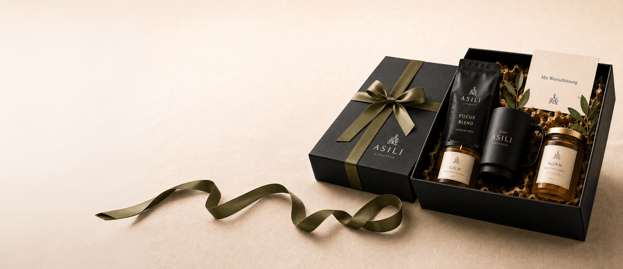 Zwei schwarze ASILI Geschenkboxen – eine mit olivfarbenem Band verschlossen, eine offen mit Kerze, Kaffee, Becher, Honig und Grußkarte